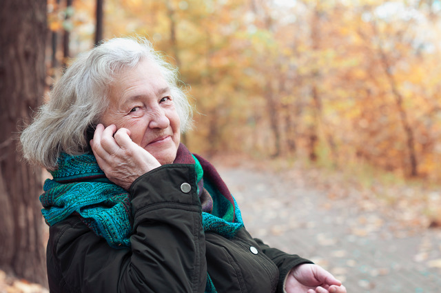elderly woman talking on the phone in an autumn park